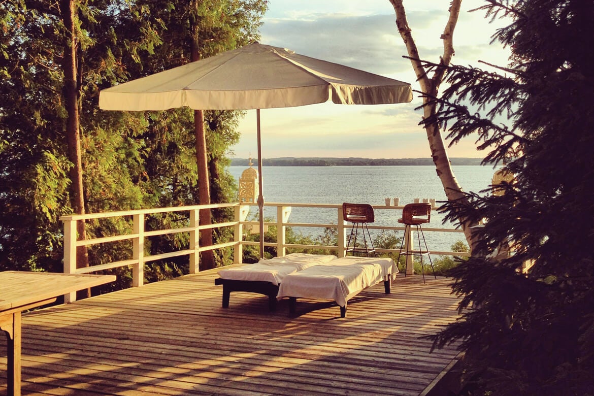 Sun chairs by the water with white umbrella