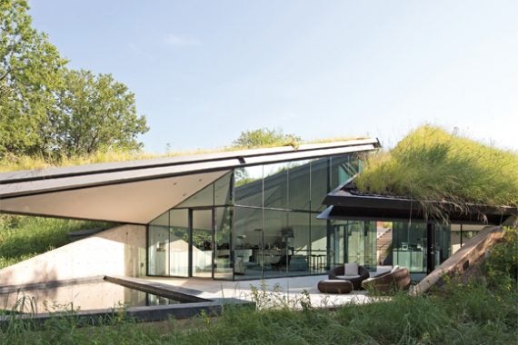 Modern concrete and glass home built into local grassy hillside
