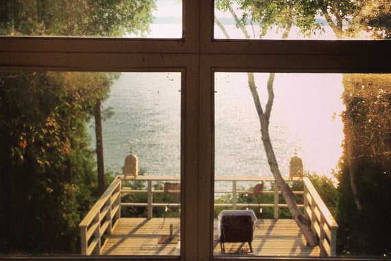 cottage window overlooking shaded deck by a lake