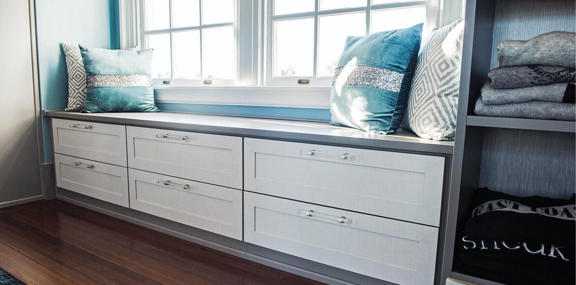 Integrated bench in light gray finish with clear hardware and blue pillows