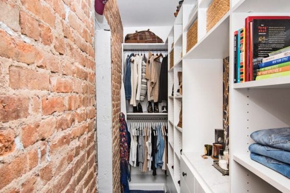 Exposed brick in walk in closet space finished in classic white