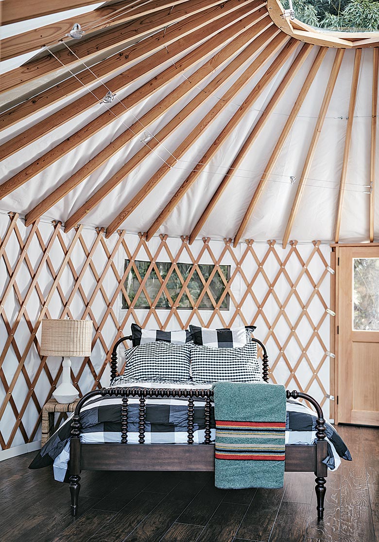 Striped bed inside of Yurt with hardwood floors