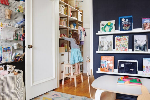 Little girl on stool reaching for something in her closet