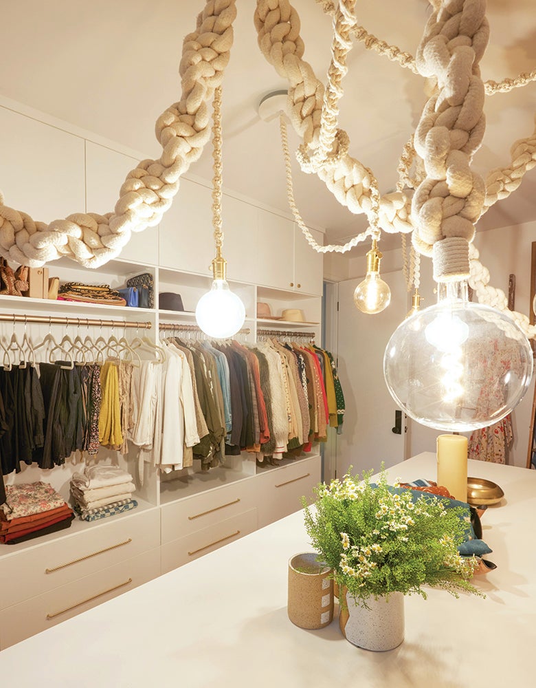 A designer walk in closet with custom cabinets and center island for Meritt Elliott designed by California Closets